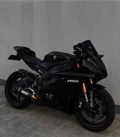 a black motorcycle parked in front of a wall with no one on it's side