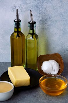 three bottles and two bowls filled with different types of soaps on a gray surface