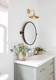 a bathroom with a sink, mirror and potted plant on the counter top in front of it