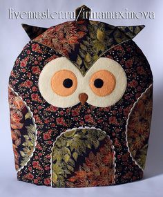 an owl made out of fabric with orange eyes and floral designs on it's body