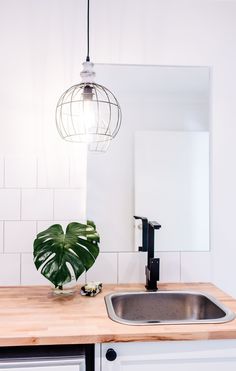 a bathroom sink under a hanging light next to a mirror