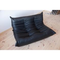 a black leather futon chair sitting on top of a hard wood floor