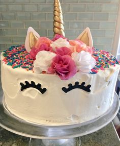 a cake decorated with white frosting and colorful sprinkles has a unicorn's face on it