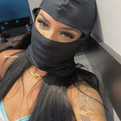 a woman wearing a black mask with her hair tied up to the side and looking at the camera