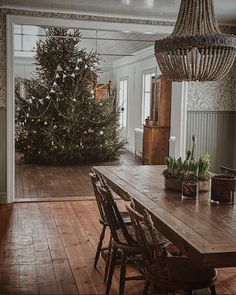 a dining room with a christmas tree in the center and wooden table on the other side