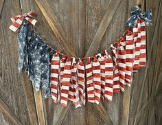 an american flag bunting hanging on a door with wood planks and weathered boards