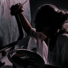 a woman is drawing on a blackboard in the dark