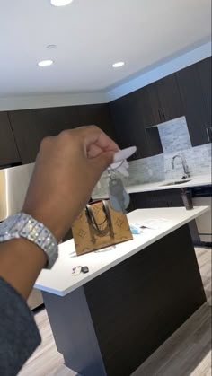 a person holding a paper bag in their hand while standing next to a kitchen counter