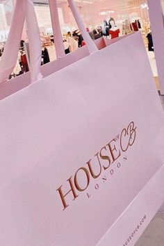 a pink shopping bag sitting on top of a white floor in front of a store