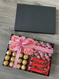 a box filled with assorted chocolates and roses on top of a wooden table