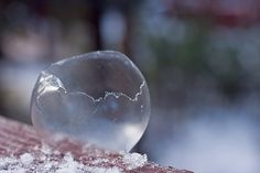 a glass ball sitting on top of a wooden table next to a snow covered ground