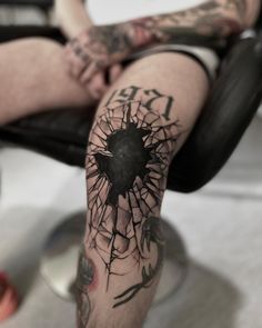 a man with tattoos on his legs sitting in a chair