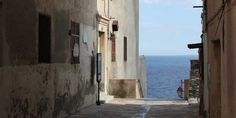 an alley way leading to the ocean on a sunny day