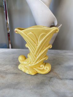 a yellow vase sitting on top of a table