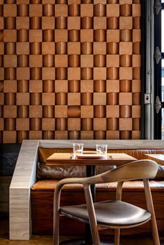 two chairs and a table in front of a wall made out of wooden blocks,