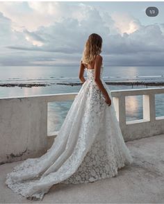 a woman in a wedding dress looking out at the ocean