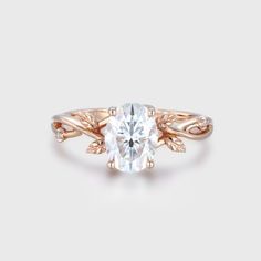 a rose gold ring with an oval cut diamond in the center and leaves on each side