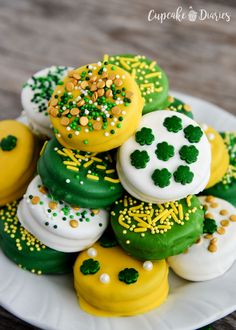 a white plate topped with lots of green and yellow decorated cookies on top of each other