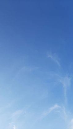 a plane flying in the blue sky with white clouds