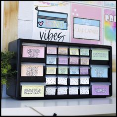 an organized desk with sticky notes and magnets on the back of it, along with a potted plant