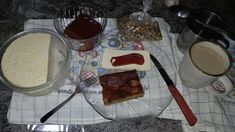 a table topped with lots of food on top of a glass plate next to cups and saucers