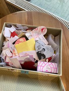 a cardboard box filled with lots of different types of paper and other things on top of a wooden table