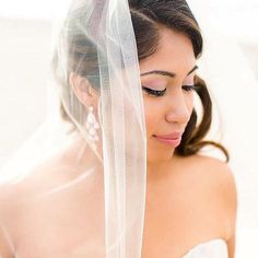 a woman wearing a wedding veil and earrings