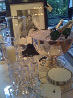 a table topped with lots of wine glasses and champagne bottles in front of a framed photo