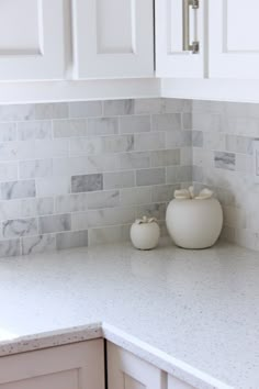 two white vases sitting on top of a kitchen counter