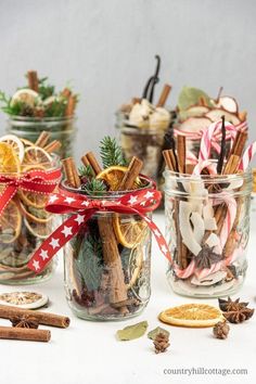 three jars filled with cinnamons, orange slices and other holiday treats sitting on a table