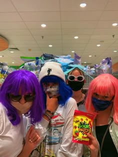 three women with pink hair and purple wigs are wearing face masks in a store