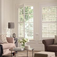 a living room filled with furniture and windows covered in shades of white shuttered window coverings