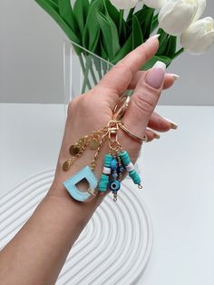 a woman's hand holding several bracelets with letters and charms on them,