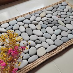 a mat made out of rope with flowers and rocks on it