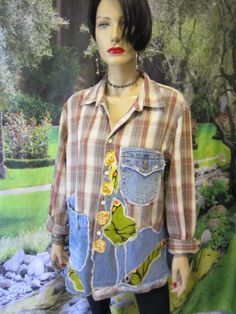 a mannequin wearing a plaid shirt with flowers and leaves on the chest, in front of a painting