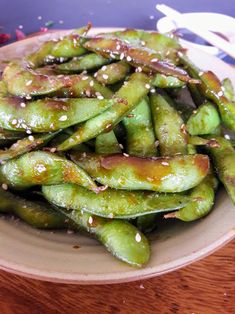 a white plate topped with green beans covered in sesame seeds