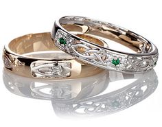 two gold wedding rings with green stones on each one and the other in white gold