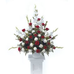 a white pedestal with red and white flowers in it