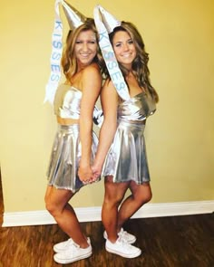 two women in silver dresses standing next to each other