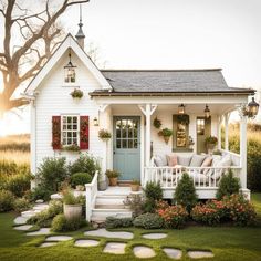 a small white house with red shutters and flowers on the front porch is shown