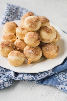 a white plate filled with sugar covered donuts on top of a blue and white napkin