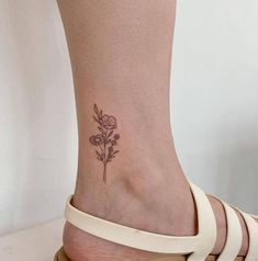 a woman's foot with a small flower tattoo on the left side of her ankle