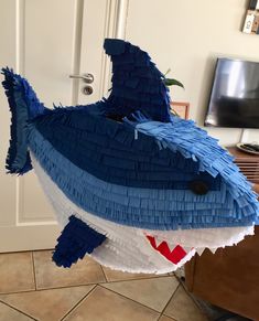 a shark made out of toilet paper sitting on top of a floor next to a door