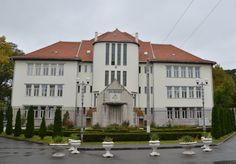 a large white building sitting on the side of a road next to a lush green park