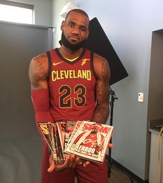 a man in a basketball uniform holding magazines