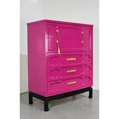 a pink chest of drawers with gold handles