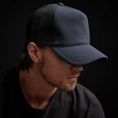 a man wearing a black and blue trucker hat, looking off to the side