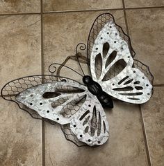 two metal butterflies sitting on top of a tiled floor