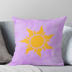 a purple and yellow pillow with the sun on it sitting on a couch next to pillows