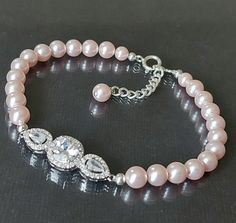 Wedding Blush Pink Light Pink Pearl CZ Silver Classic Bridal Bracelet. PLEASE READ ITEM DESCRIPTION and SHOP POLICIES before placing your order, and contact me with any questions! BRACELET is about 7.50 inches (19cm) long plus 1" extender chain. PINK PEARL JEWELRY: https://www.etsy.com/shop/LanaChayka?ref=seller-platform-mcnav&search_query=pink+pearls BRIDAL EARRINGS SECTION: https://www.etsy.com/shop/LanaChayka?ref=seller-platform-mcnav§ion_id=11638940 BRIDAL JEWELRY SETS SECTION: https://www.etsy.com/shop/LanaChayka?ref=seller-platform-mcnav§ion_id=25839214 BRIDAL NECKLACES SECTION: https://www.etsy.com/shop/LanaChayka?ref=seller-platform-mcnav§ion_id=11638944 Handmade bracelet, is made with Light Pink Rosaline Blush Pink color premium quality European round crystal pearls, Rhodium Plate Pink Pearl Bracelet For Wedding, Crystal Bracelet With Round Beads For Wedding, Adjustable Round Pearl Bracelet For Wedding, Elegant Crystal Bracelet For Wedding, Adjustable Round Crystal Bracelet For Wedding, Elegant Round Crystal Bracelet For Wedding, Hand Set Beaded Bangle Bracelets For Wedding, Adjustable Silver Bridal Accessories For Bridal Shower, Pink Beaded Bangle Bracelets For Wedding